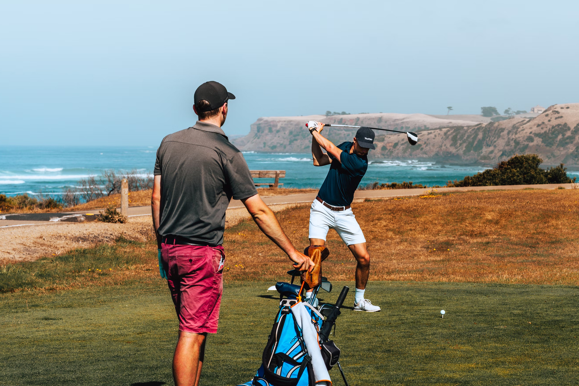 A team of golfers, one of which is mid swing