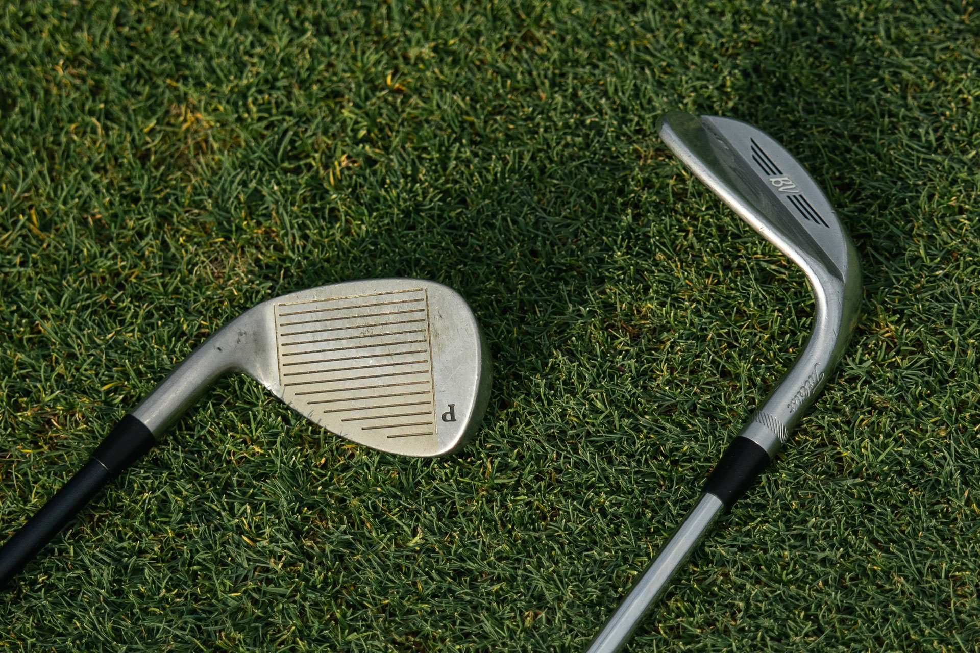 Two golf clubs laying on a putting green