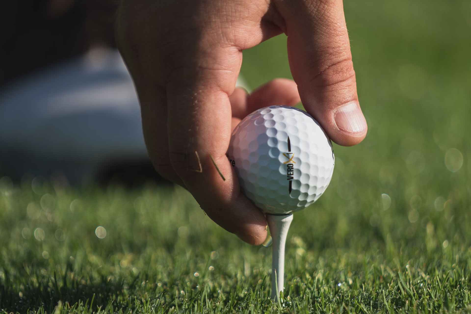 A man placing a golf ball on a tee