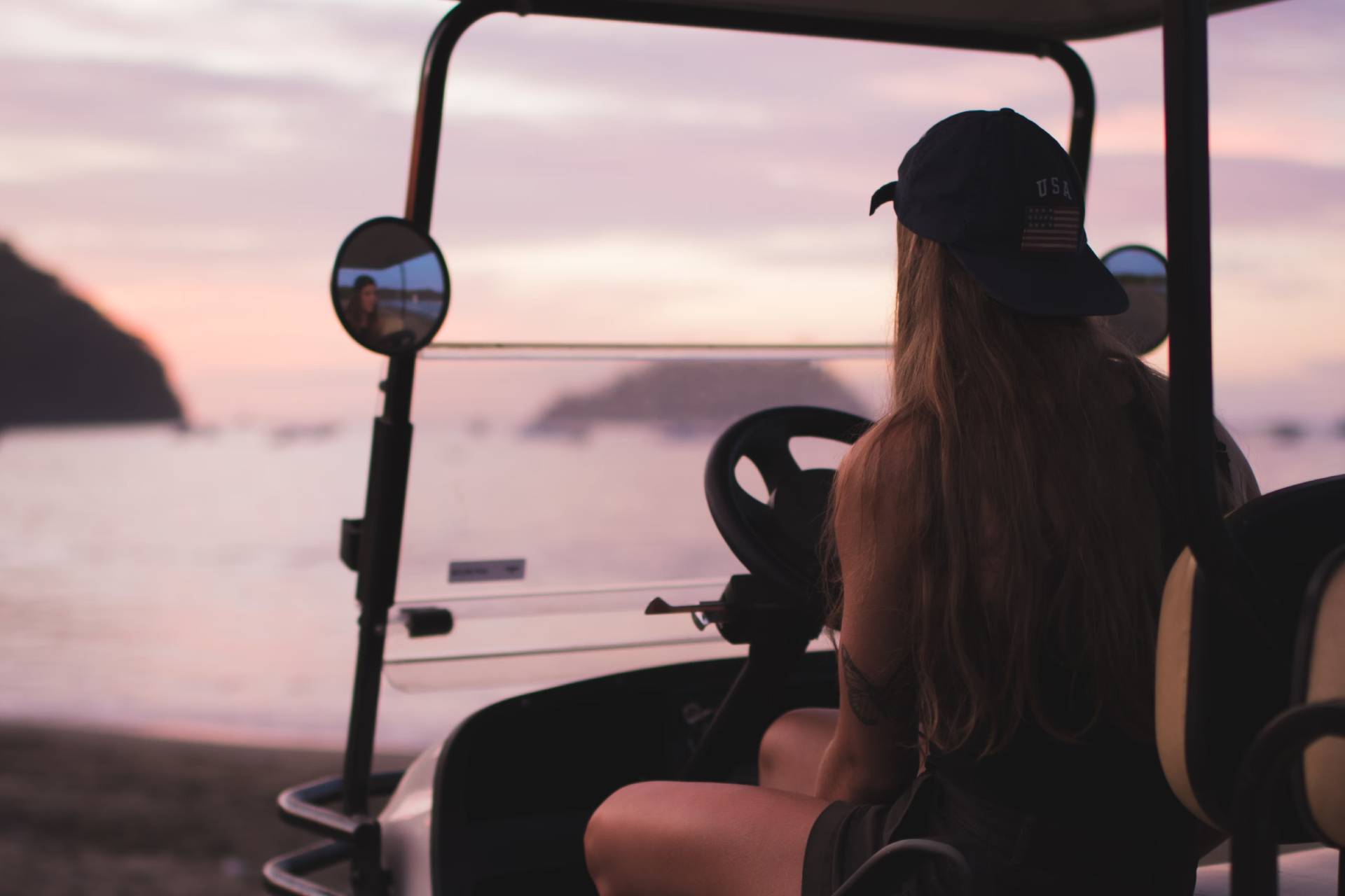 A lady in a black cap sitting in a golf cart