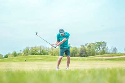 A man mid way through a golf swing